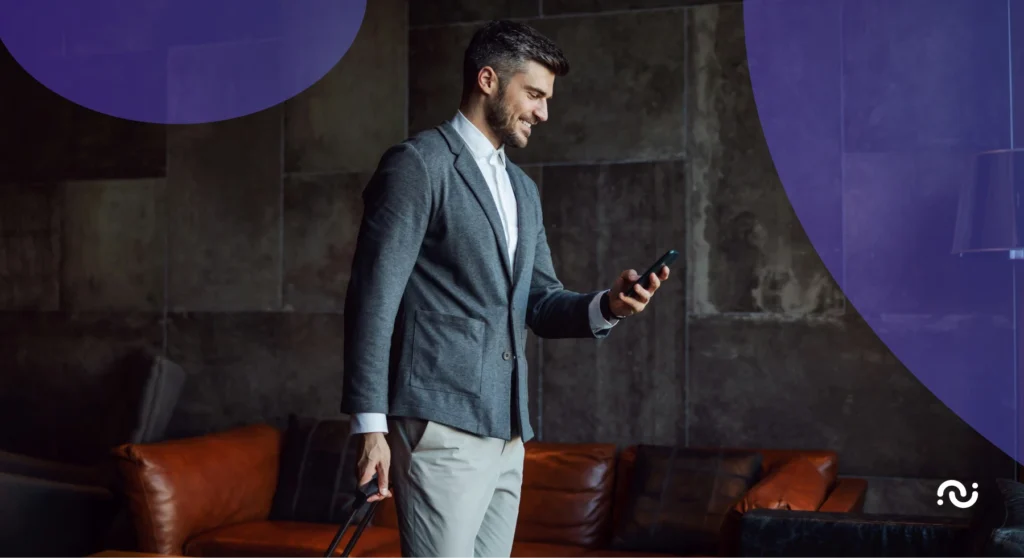 A hotel guest in a room is holding a suitcase and is using hotel guest apps